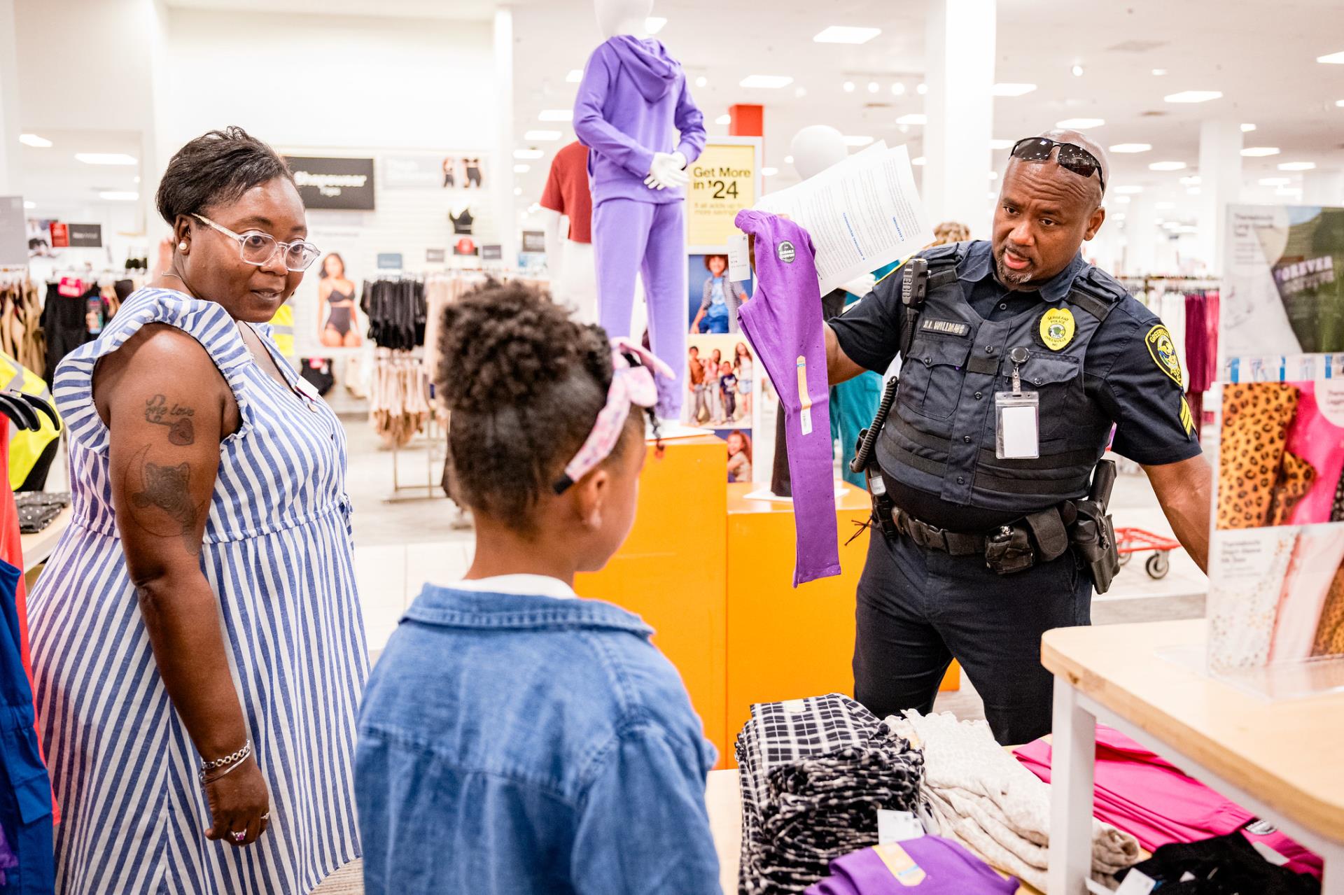 police officer holding up clothes with child