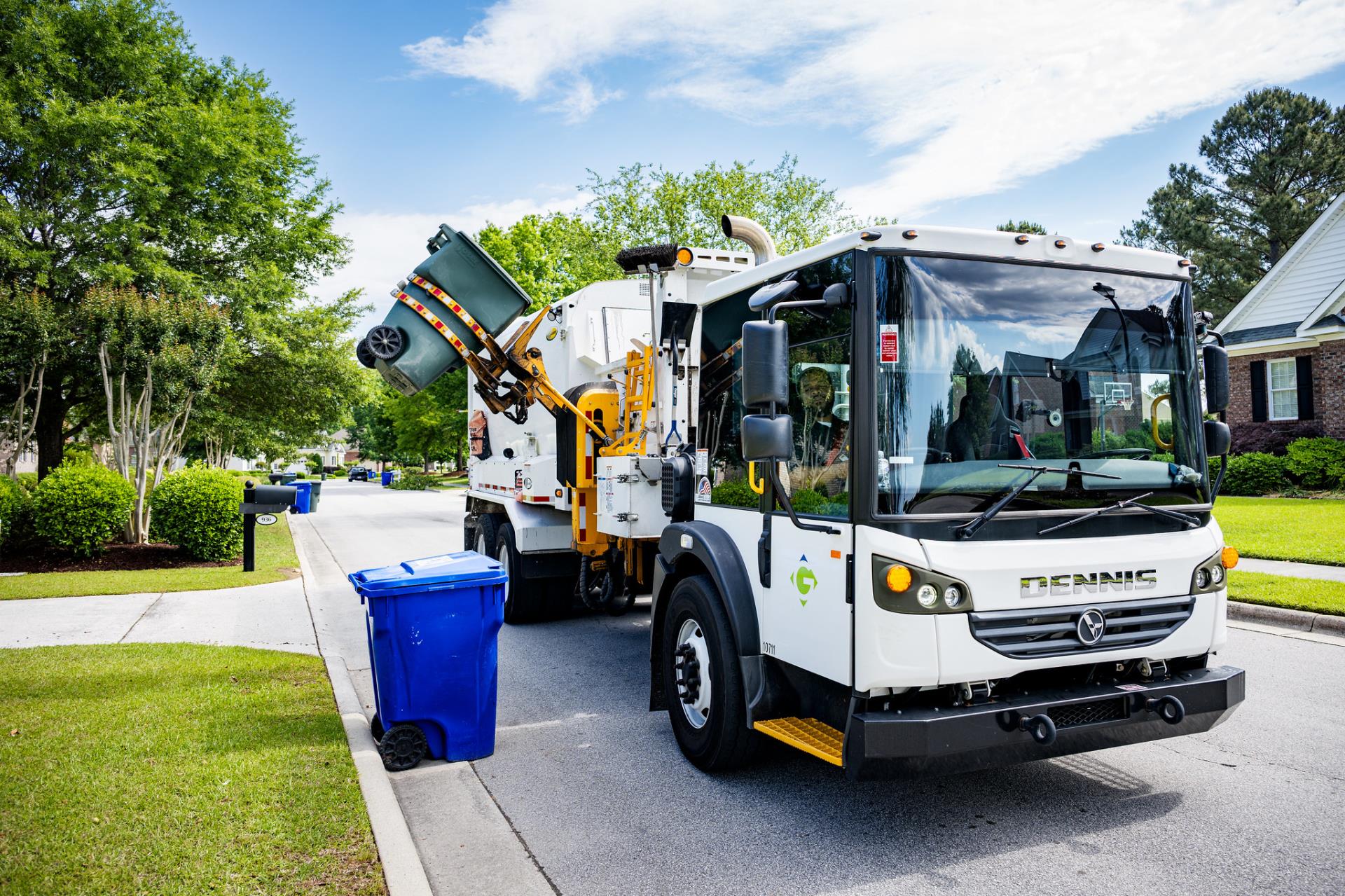 trash truck collecting a can from the side of the street